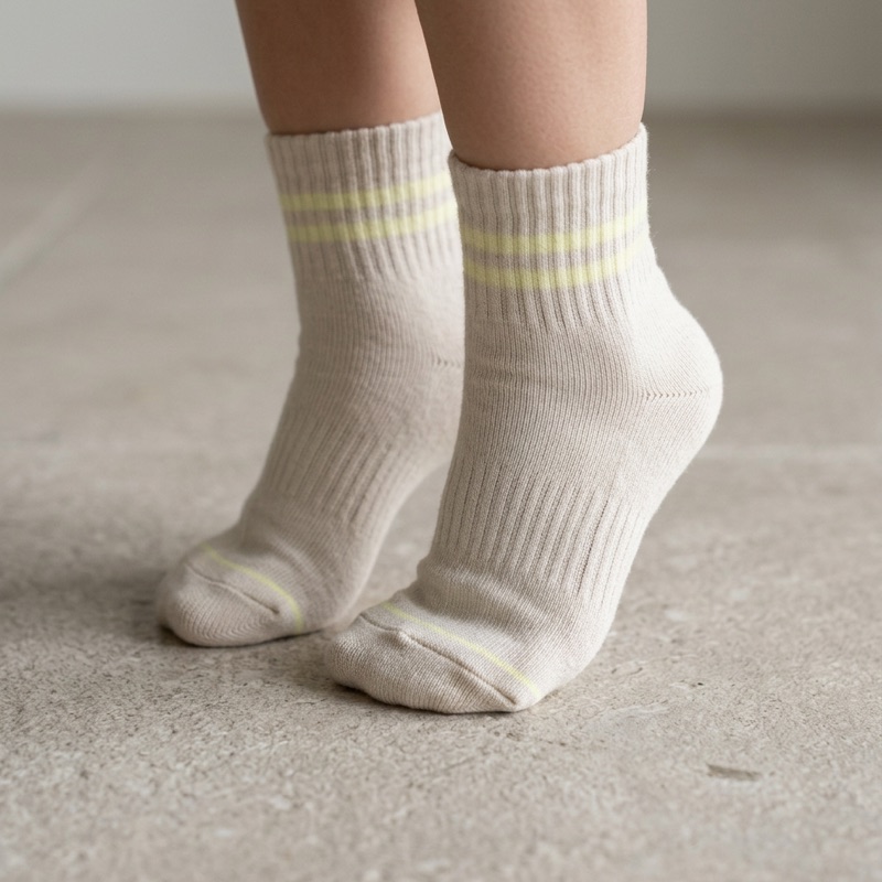 A child's feet in undyed cotton STROMA socks, up on tiptoe on a stone floor